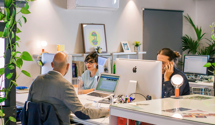 Drei Arbeitskollegen sitzen am PC, arbeiten, unterhalten sich.